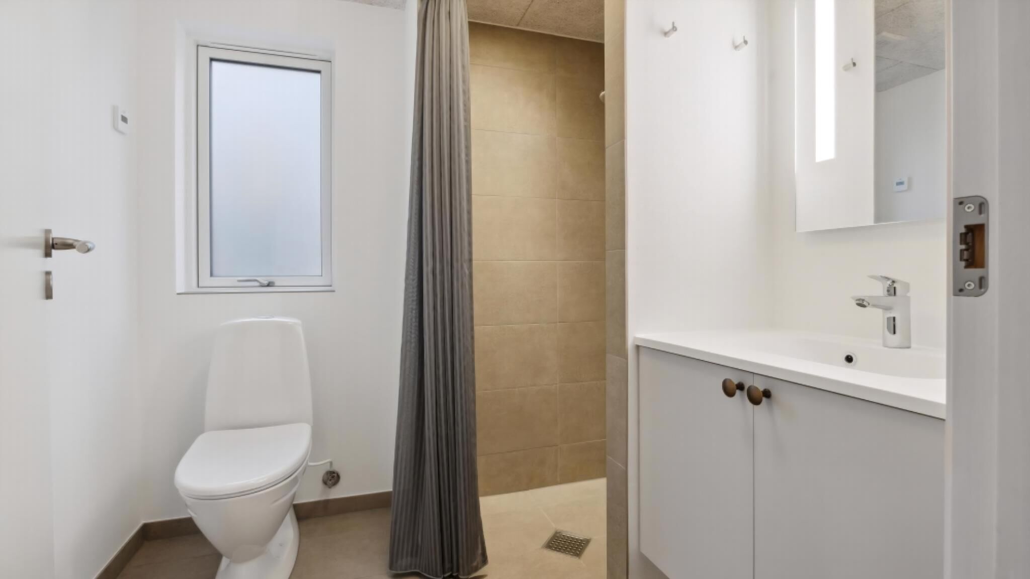 Une salle de bain comprenant des toilettes, une fenêtre, un rideau de douche, un lavabo et un miroir.