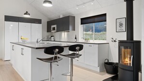 A modern kitchen with a central island, bar stools, a stove, and a window with a view. - VillaVilla 732 - Olpenitz, Deutschland (Kappeln)