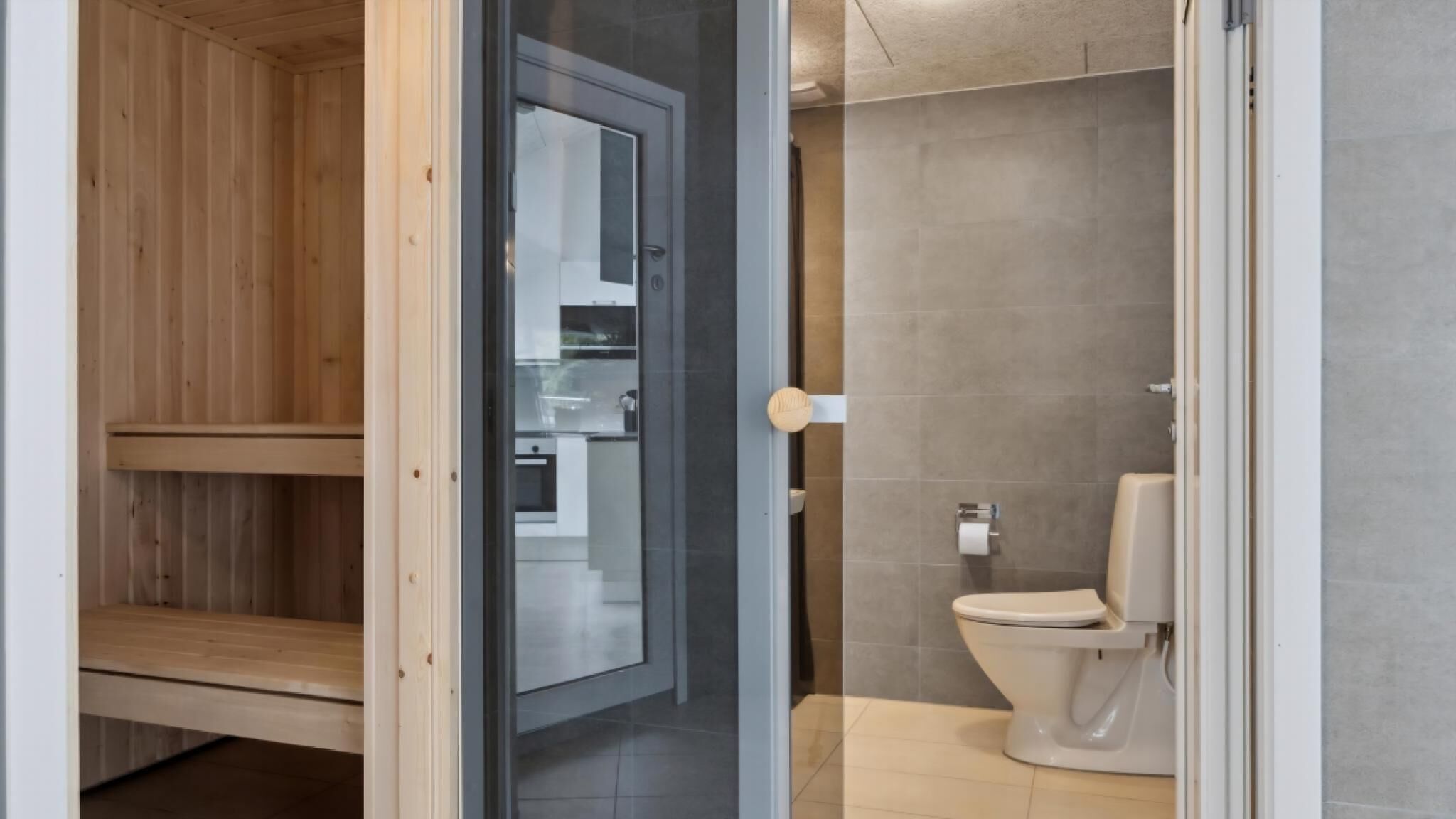 A modern bathroom with a toilet, a shower area, and a wooden bench.