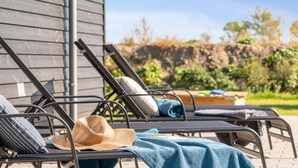 A row of sun loungers with towels and a straw hat on one of them.
