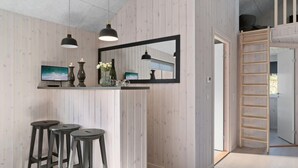 A modern interior with a wooden wall, a large mirror, a TV, and three stools.