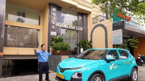 Un hôtel appelé Hoàng Anh Star, avec une voiture bleue garée devant.