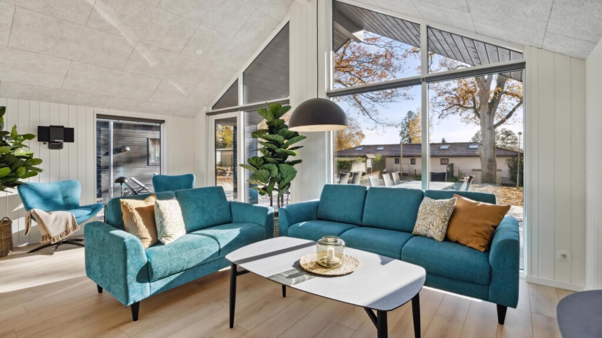 A spacious living room with a large window, a blue sofa set, and a coffee table.