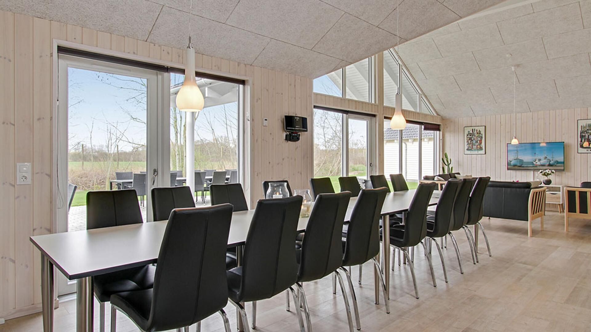 A conference room with a long table, black chairs, and pendant lights.