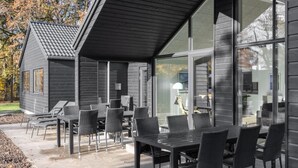 Un edificio moderno con un patio amoblado con asientos al aire libre y un amplio ventanal.