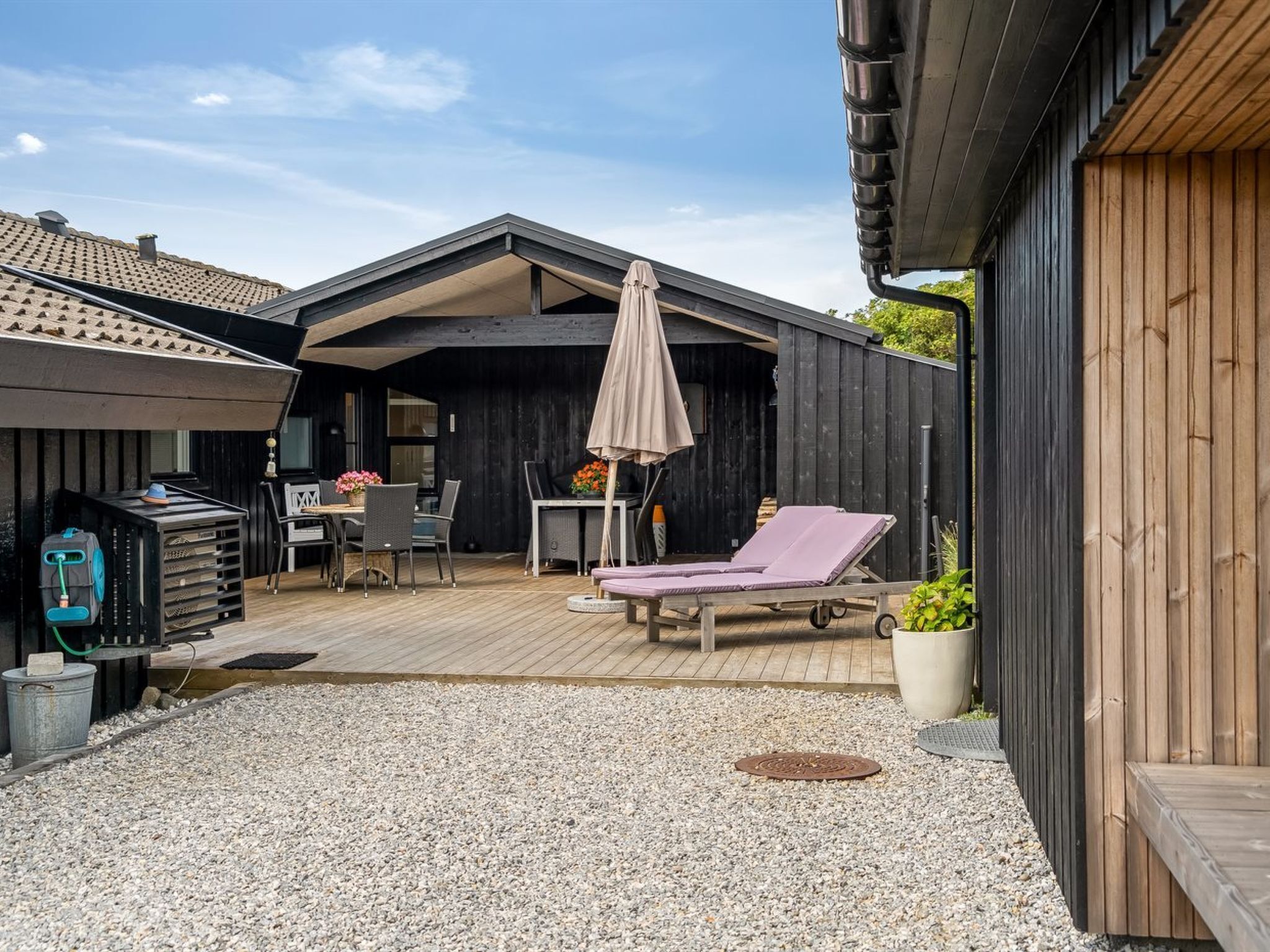 A covered patio with a grill, outdoor seating, and a lounge area.