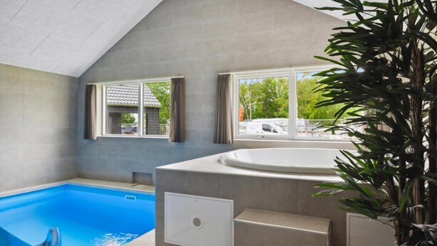 Una piscina interior con vistas a una zona residencial a través de amplias ventanas.