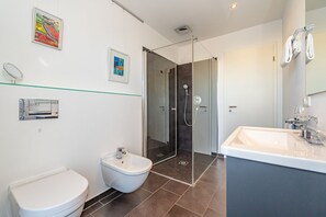 A modern bathroom with a glass shower enclosure, a white toilet, and a large sink. - High end penthouse - Exclusive penthouse on Sylt with balcony, close to the beach. (Sylt)