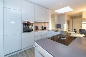 A modern kitchen with a built-in oven, coffee maker, and a sleek island with a stovetop.