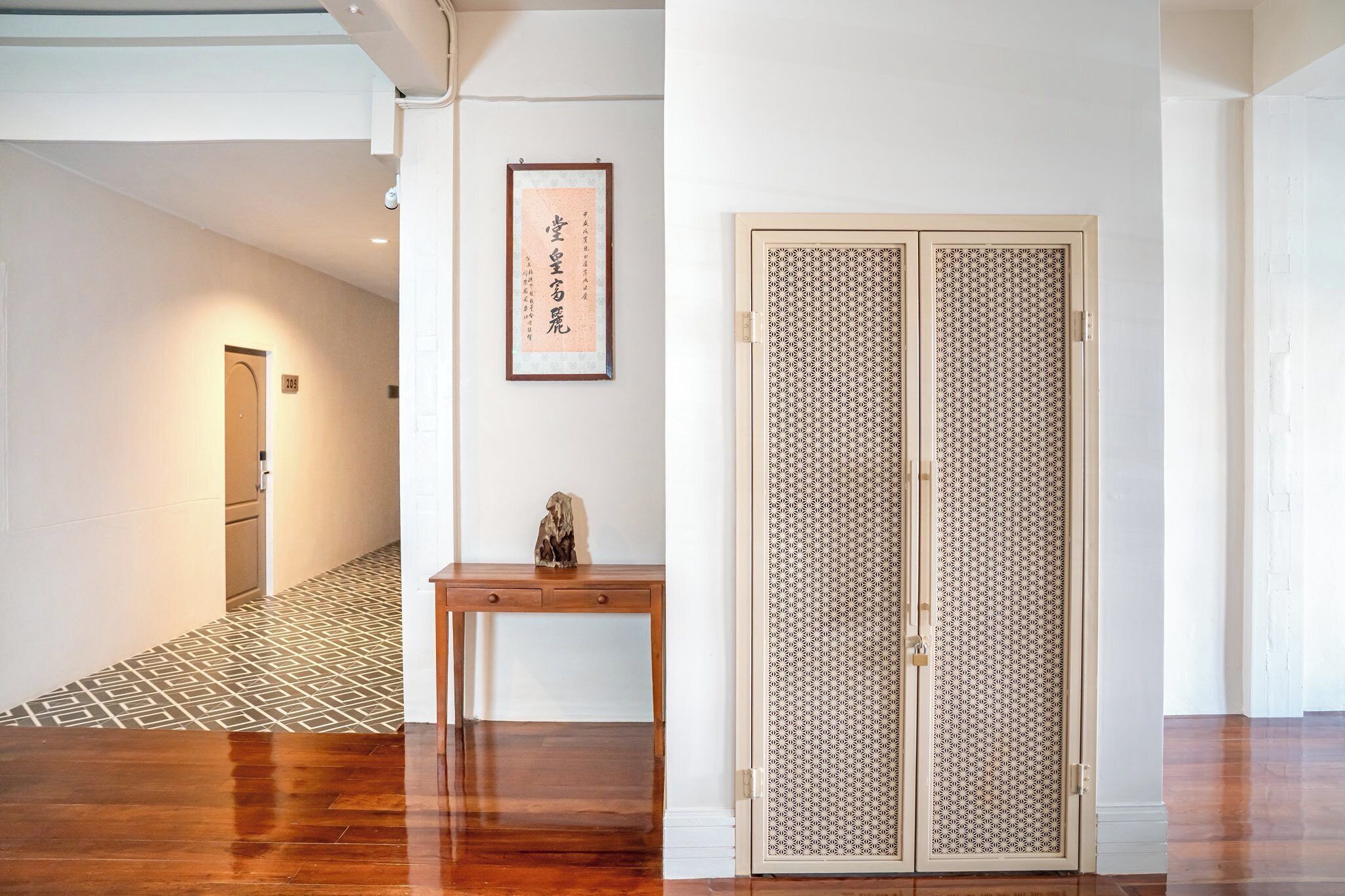 A hallway with a wooden floor, a framed picture on the wall, and a traditional sliding door.