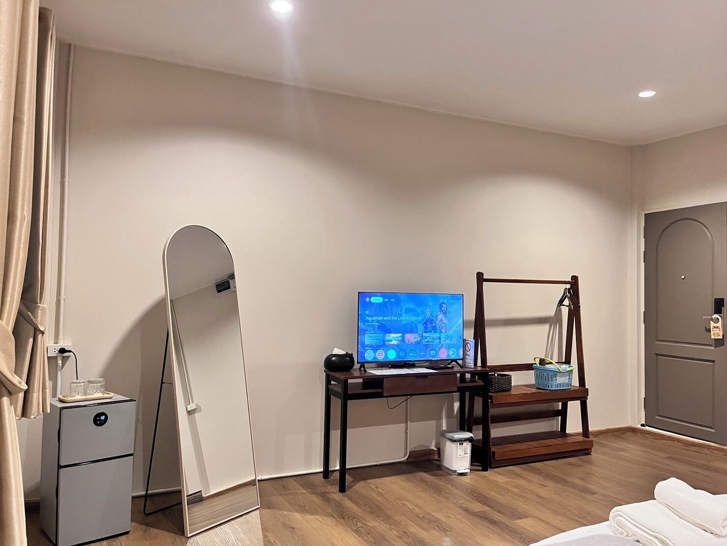 Habitación de hotel con suelo de madera, un escritorio con computadora, espejo, cama y armario.