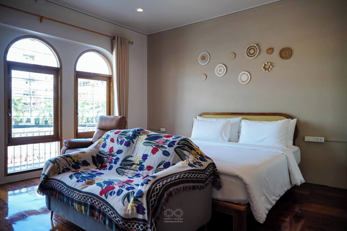 Una habitación de hotel con una cama, una silla y un ventanal con cortinas.