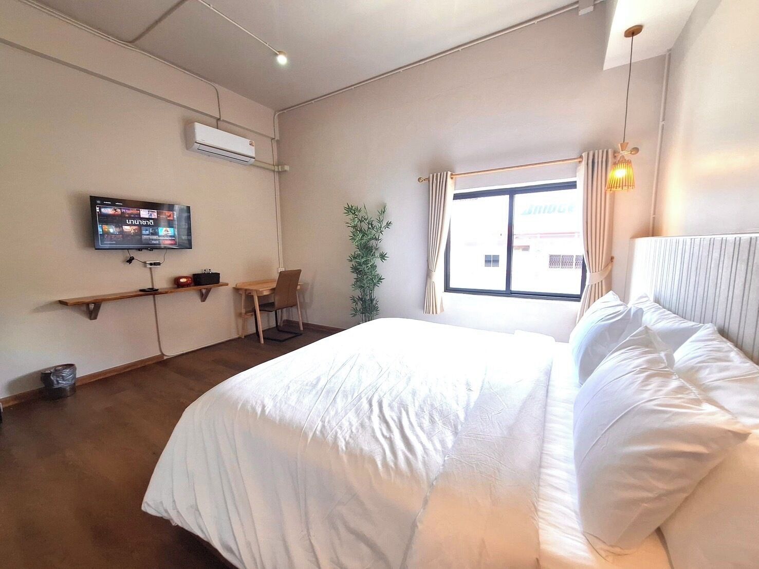Une chambre d’hôtel avec un lit, un bureau, une chaise, une télévision et une fenêtre avec des rideaux.
