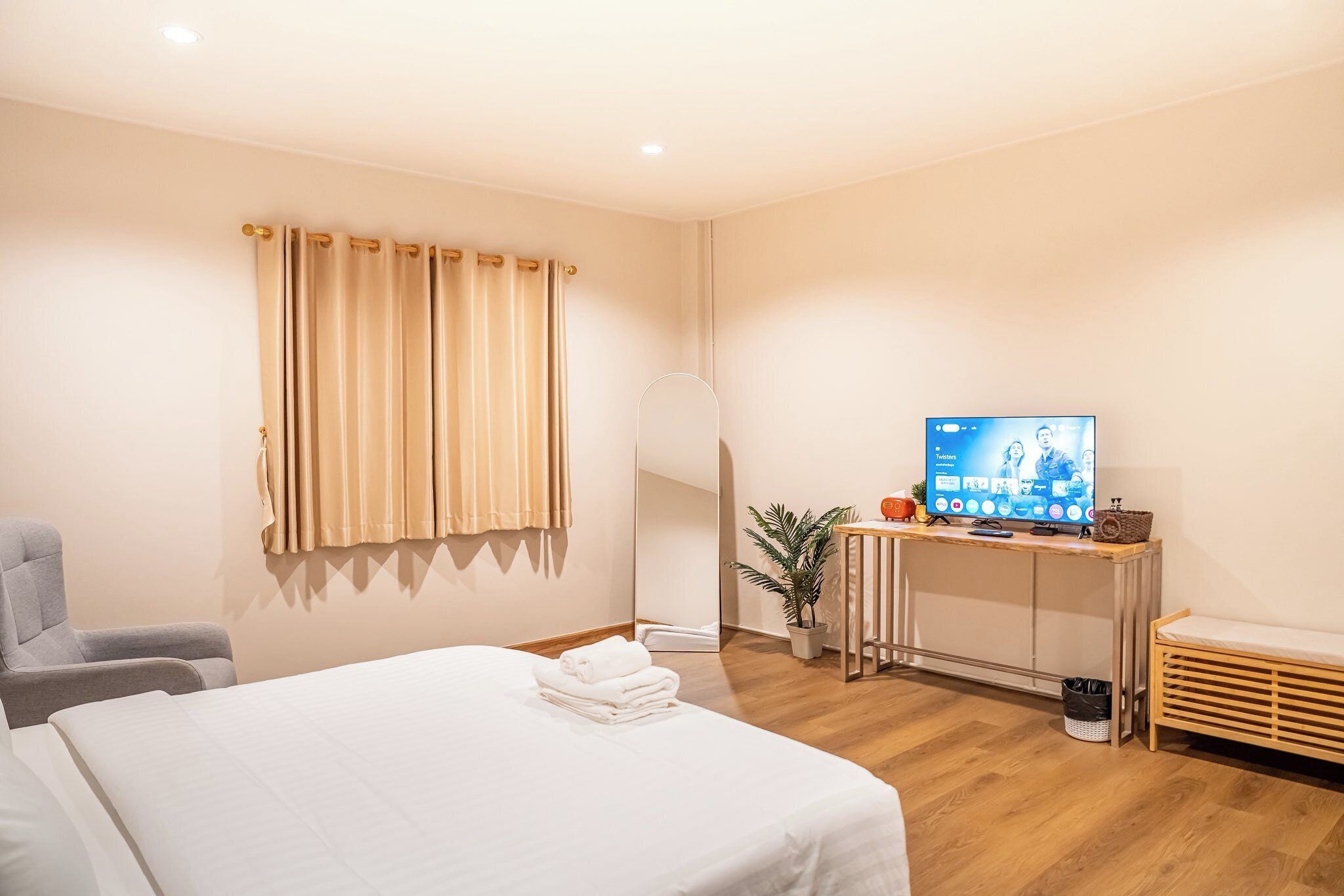 Habitación de hotel con cama, escritorio con televisor, silla y planta en maceta.