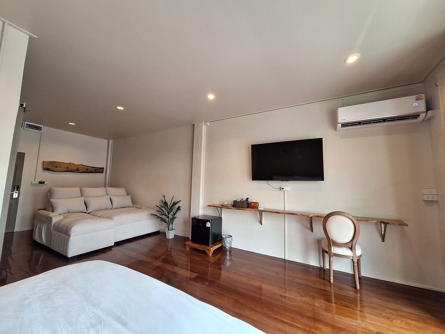 Un dormitorio moderno con una cama, un televisor montado en la pared y un equipo de aire acondicionado.
