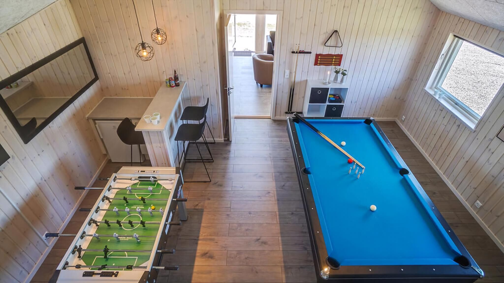 A pool table, a foosball table, and a bar area with seating.