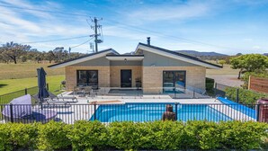 Une maison moderne dotée d’une piscine, d’un patio avec mobilier d’extérieur et offrant une vue sur le paysage environnant.
