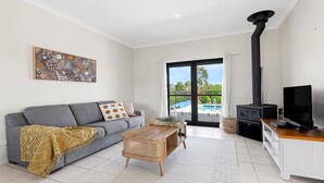 Ein modernes Wohnzimmer mit grauem Sofa, Couchtisch aus Holz, Fernseher und Kamin.