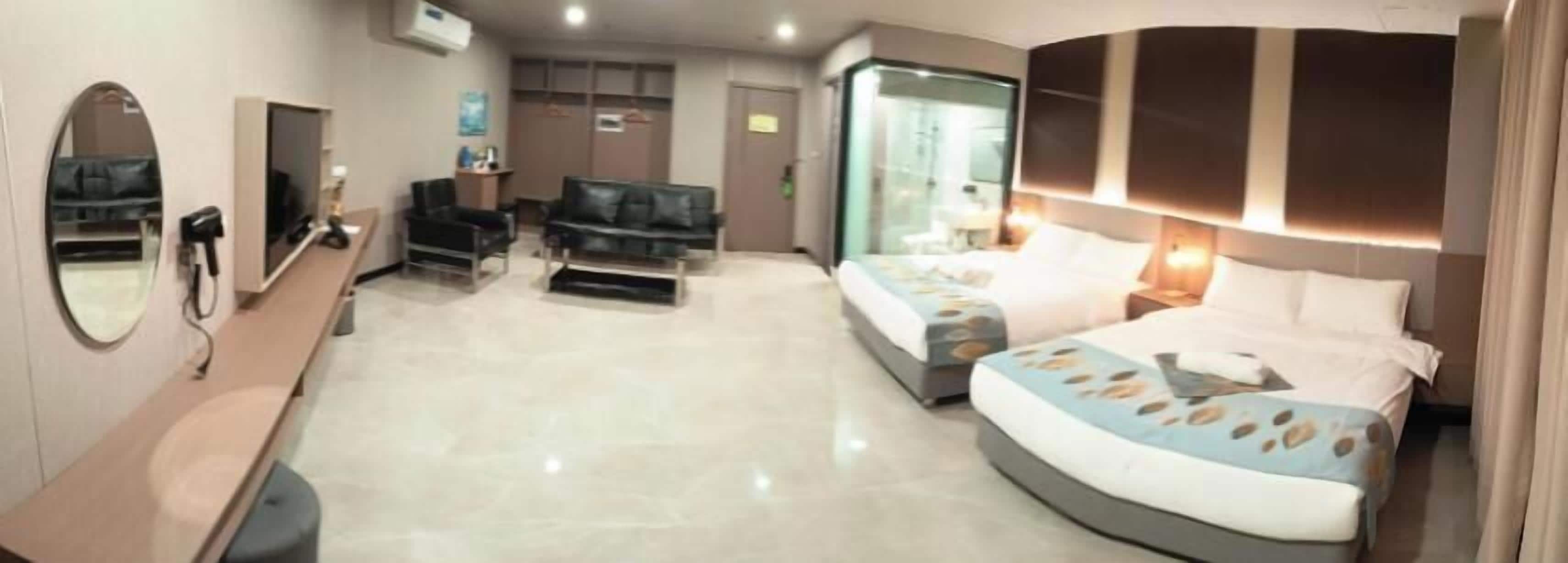 A hotel room with a bed, a sofa, a desk, and a mirror.
