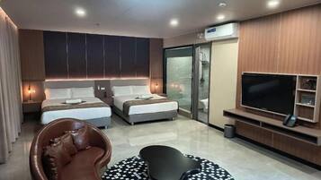 Ein modernes Hotelzimmer mit zwei Betten, einem Fernseher, einer Couch und einer Duschkabine.