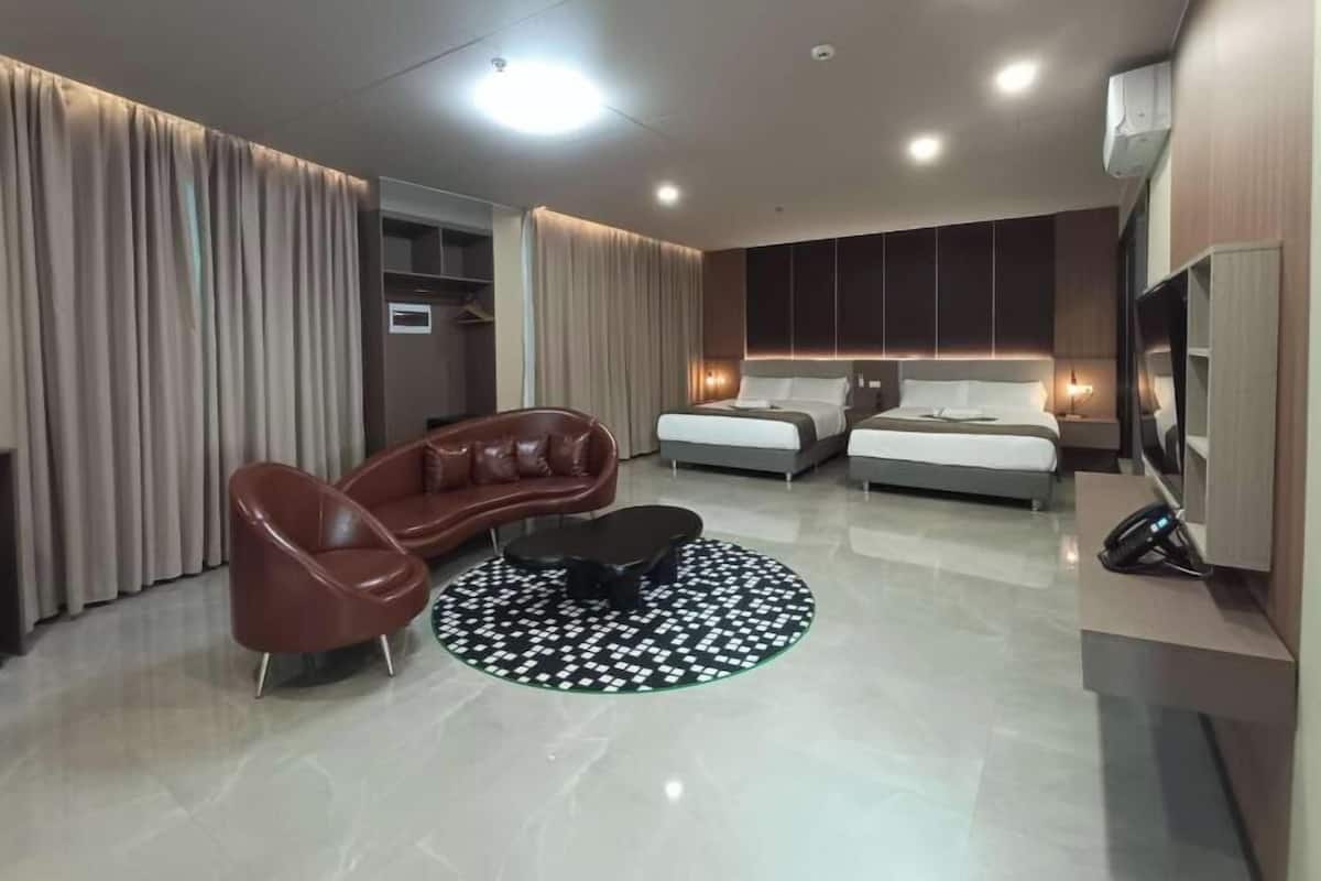 A modern hotel room with a sofa, two beds, a TV, and a minibar.
