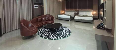 Une chambre d’hôtel moderne équipée d’un canapé, de deux lits, d’une télévision et d’un mini-bar.
