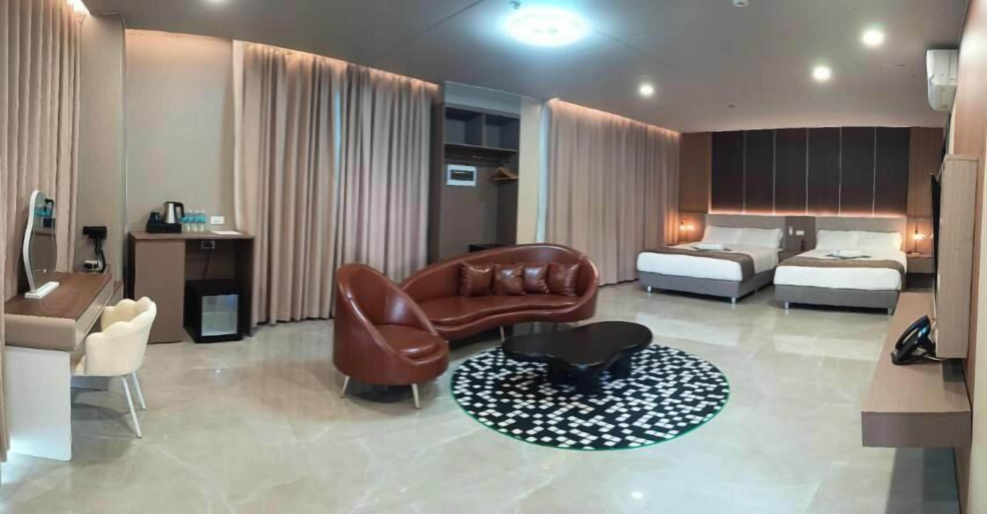 A modern hotel room with a sofa, a bed, a desk, and a coffee machine.