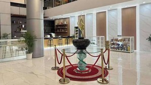 A modern lobby with a central decorative fountain, a reception desk, and a seating area on the upper level. - Skyport Hotel (Parañaque)