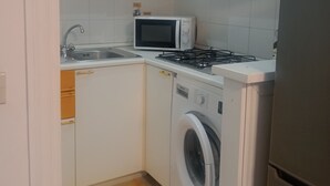 Una cocina compacta con lavadora, microondas y estufa.