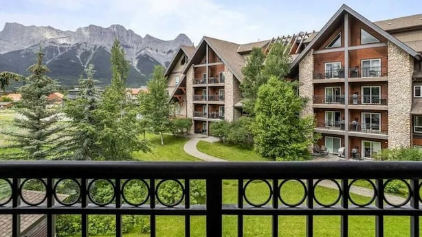 A hotel with multiple floors, balconies, and a view of mountains.