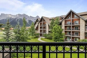 A hotel with multiple floors, balconies, and a view of mountains.