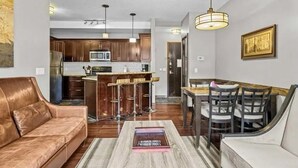 A modern living room with a leather sofa, a coffee table, and a dining area with a wooden table and chairs.