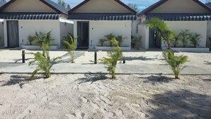 A row of three white buildings with dark roofs, each with a door and a small garden area with palm trees. - WHITE BEACH RESORT LONGSET (Koh Rong)
