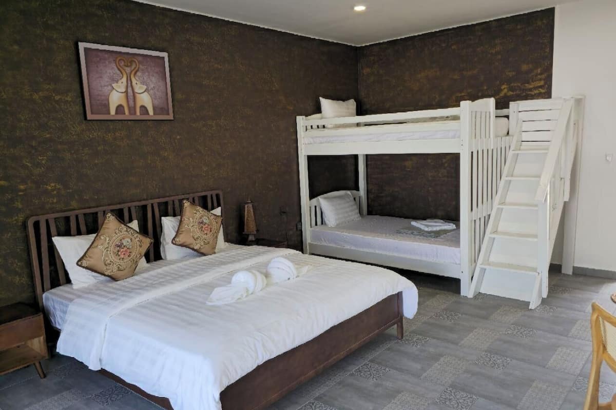 Une chambre avec un grand lit, un lit superposé et une échelle.