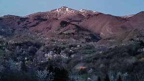A mountain with a village at its base, featuring houses and trees.