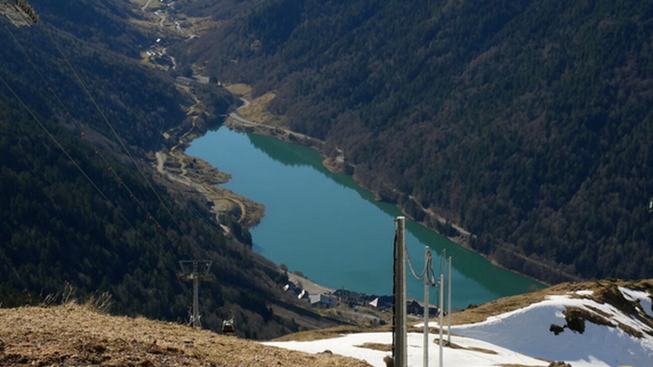 Un paysage montagneux avec un lac, une structure en bois et une ligne électrique.