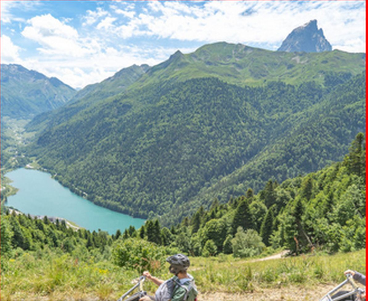 Paisaje de montaña con un lago y dos personas en karts de montaña.