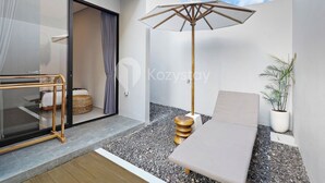 Ein moderner Außenbereich mit Tisch, Bank und Sonnenschirm.
