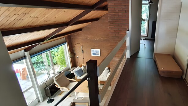 A modern interior with a wooden ceiling, a staircase, and a view of the outdoors.