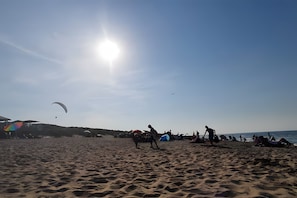 Ein Strand mit Menschen, Zelten und einem klaren Himmel.