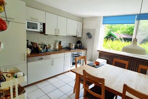 Eine moderne Küche mit weißen Schränken, einer Mikrowelle und einem Essbereich mit Tisch und Stühlen.