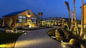 A modern building with a wooden facade, a circular window, and a pathway leading to a bridge. - venecia resort fayoum (Yusuf as-Sidiq)