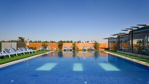 A clear blue swimming pool with lounge chairs and a glass building structure. - venecia resort fayoum (Yusuf as-Sidiq)
