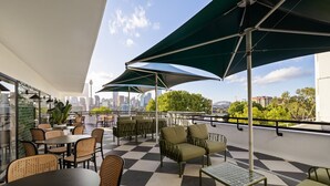 Terraza en la azotea con asientos al aire libre, vista del horizonte urbano y piso con estampado de cuadros.