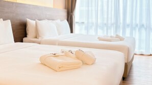 A hotel room with two beds, each with neatly folded towels and a headboard. - Cottonhouz, KK Times Square by Ayuhouz (Kota Kinabalu)