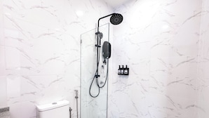 A modern bathroom with a glass-enclosed shower, a toilet, and a wall-mounted soap dispenser. - Cottonhouz, KK Times Square by Ayuhouz (Kota Kinabalu)