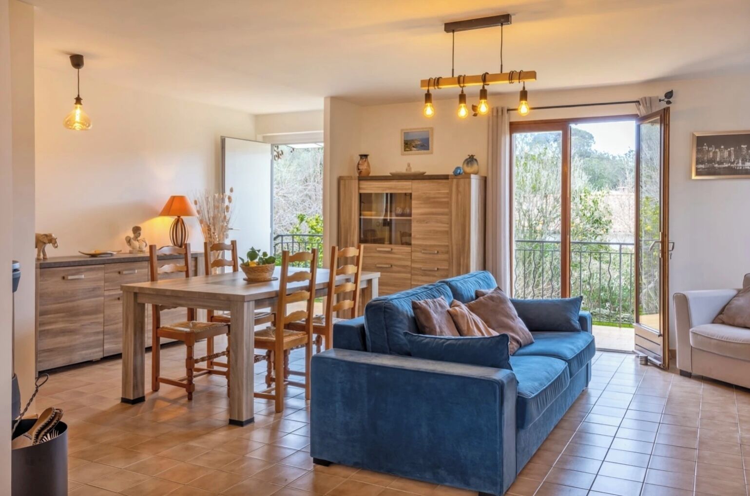 Un salon moderne avec un canapé bleu, une table à manger en bois et des chaises. On y trouve également un coin cuisine avec un comptoir et des placards.