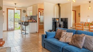 Una sala de estar moderna con un sofá azul, una zona de cocina con estufa y un comedor con sillas de madera.