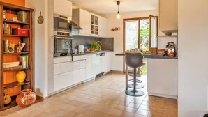 Una cocina moderna con armarios blancos, horno empotrado y una zona de bar con taburetes.