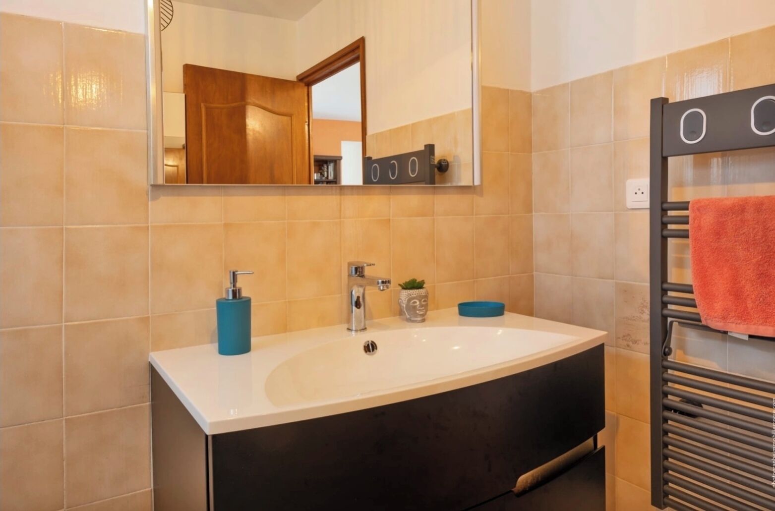 Ein Badezimmer mit einem großen Waschbecken, einem Spiegel, einem Handtuchhalter und einer Toilette.